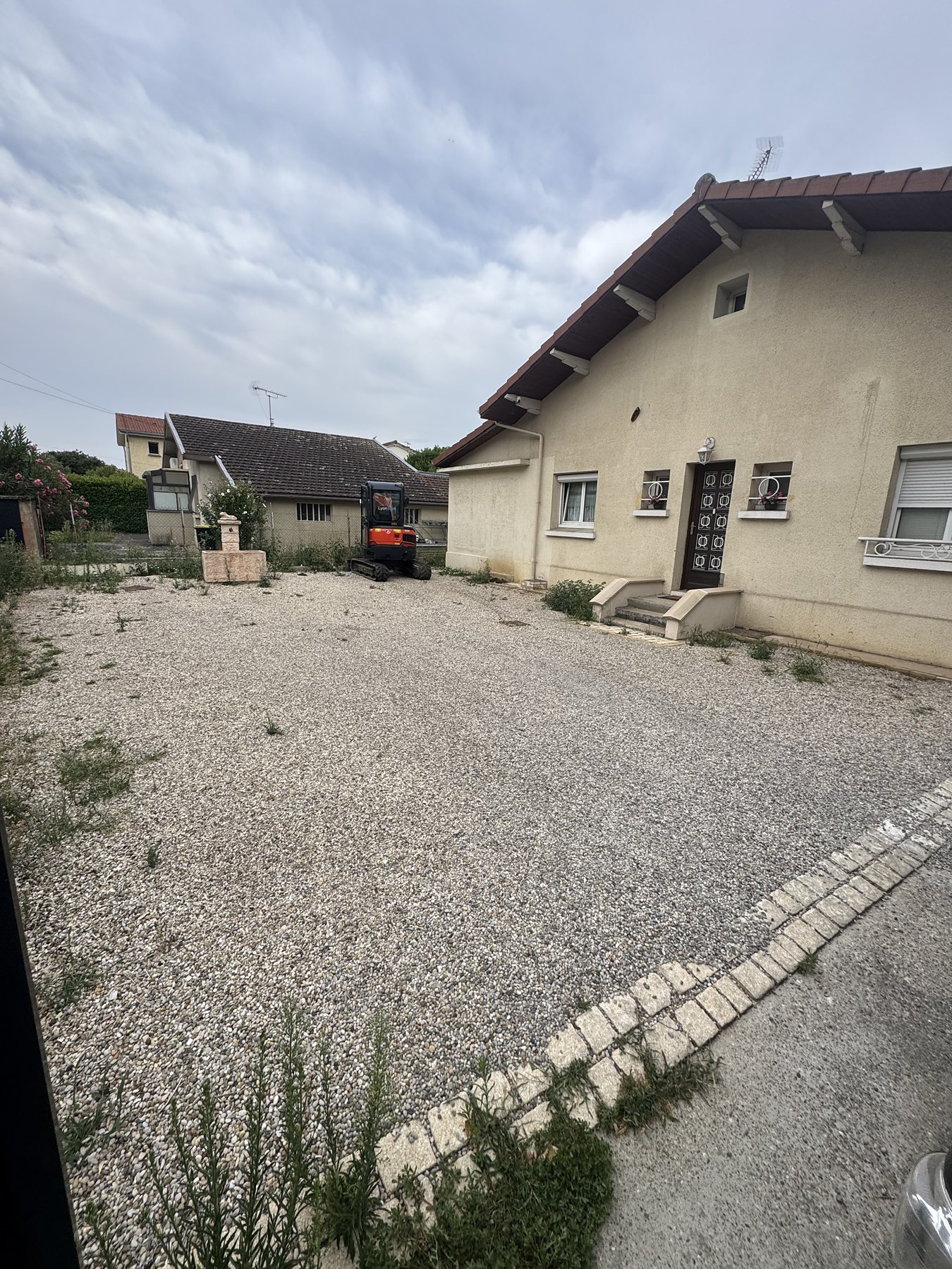 Avant : cour en gravier envahie par les herbes avant terrassement
