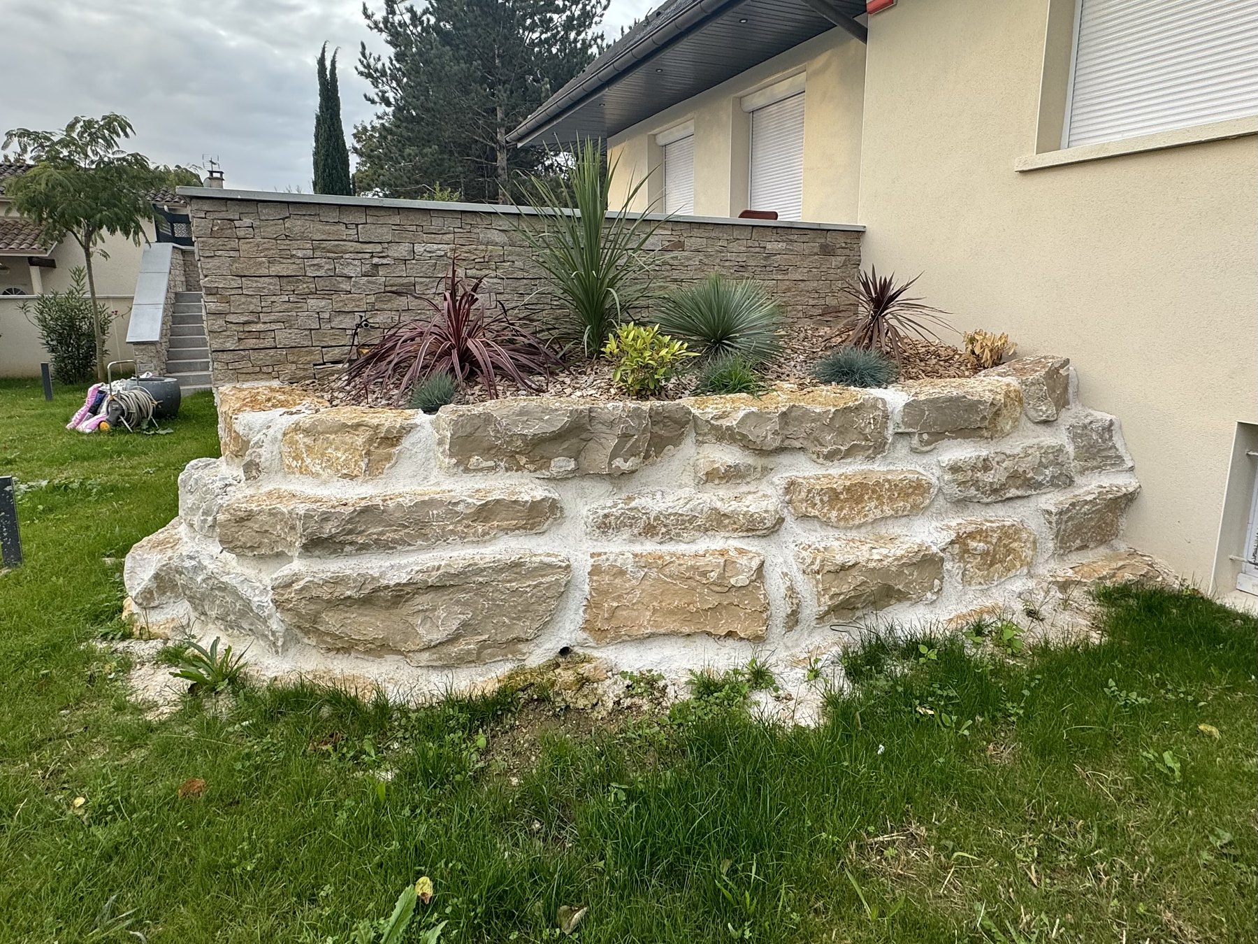 Muret de soutènement en pierre naturelle avec massif planté